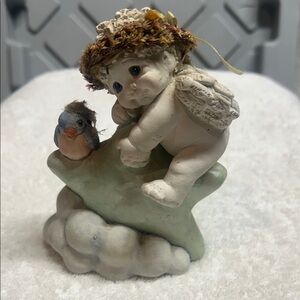 A vintage Dreamsicles 'Swing on a Star' resin figurine with a cherub and bird.